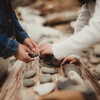 Little girls stacking stones on a piece of driftwood at the beach