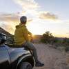Mature man watches sunset over desert from vehicle
