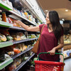 Smiling woman doing shopping in supermarket and deciding what to buy. Happy woman shopping in a grocery store and holding shopping basket. Mature latin woman buying vegetable in a grocery shop.