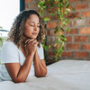 Woman kneeling praying in her room