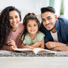 Portrait Of Happy Parents Reading Book With Their Little Daughter
