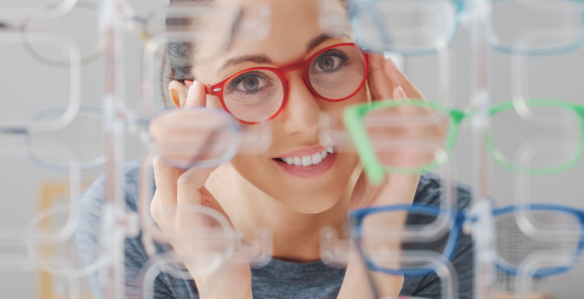 Happy woman at the optician shop, she is looking at the eyewear collection