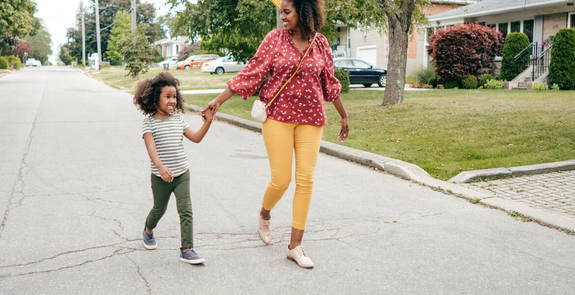 Mom and daughter walking together through the neighborhood.