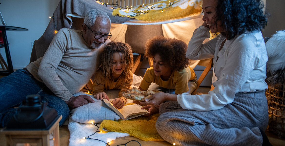 Grandparents and grandchildren enjoying a moment in a homebuilt fort tent.