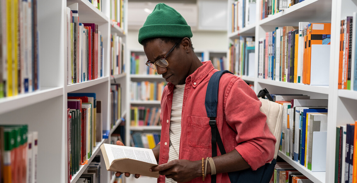 Curious reader looking at a book in a library aisle
