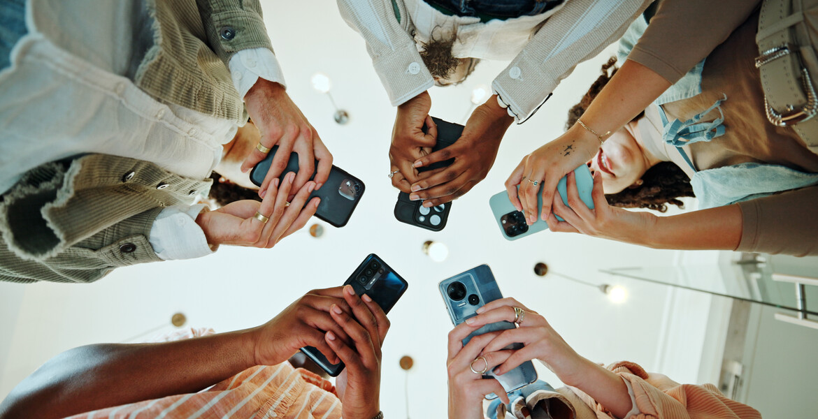 People, circle and phones for university registration, online and teamwork in education on campus. Students, low angle and huddle for project solidarity in college, collaboration and united learning