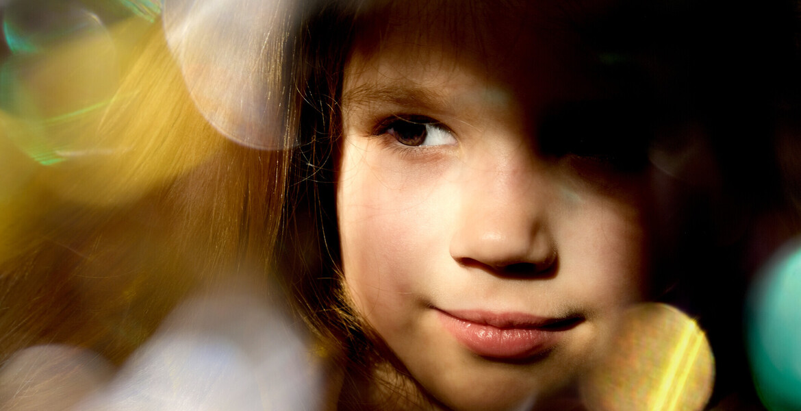 Close up dreamy face of pretty little child girl with xmas lights bokeh.