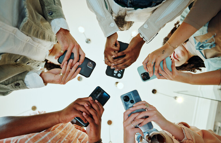 People, circle and phones for university registration, online and teamwork in education on campus. Students, low angle and huddle for project solidarity in college, collaboration and united learning